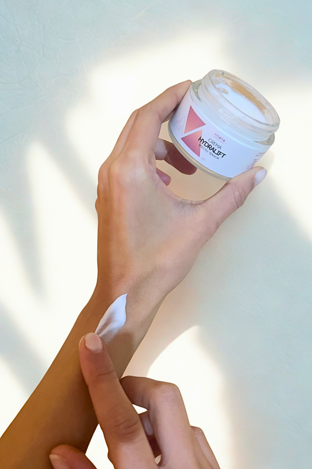 Crema hydralift abierto mostrando textura. Una mano coge el tarro y muestra la textura en su brazo